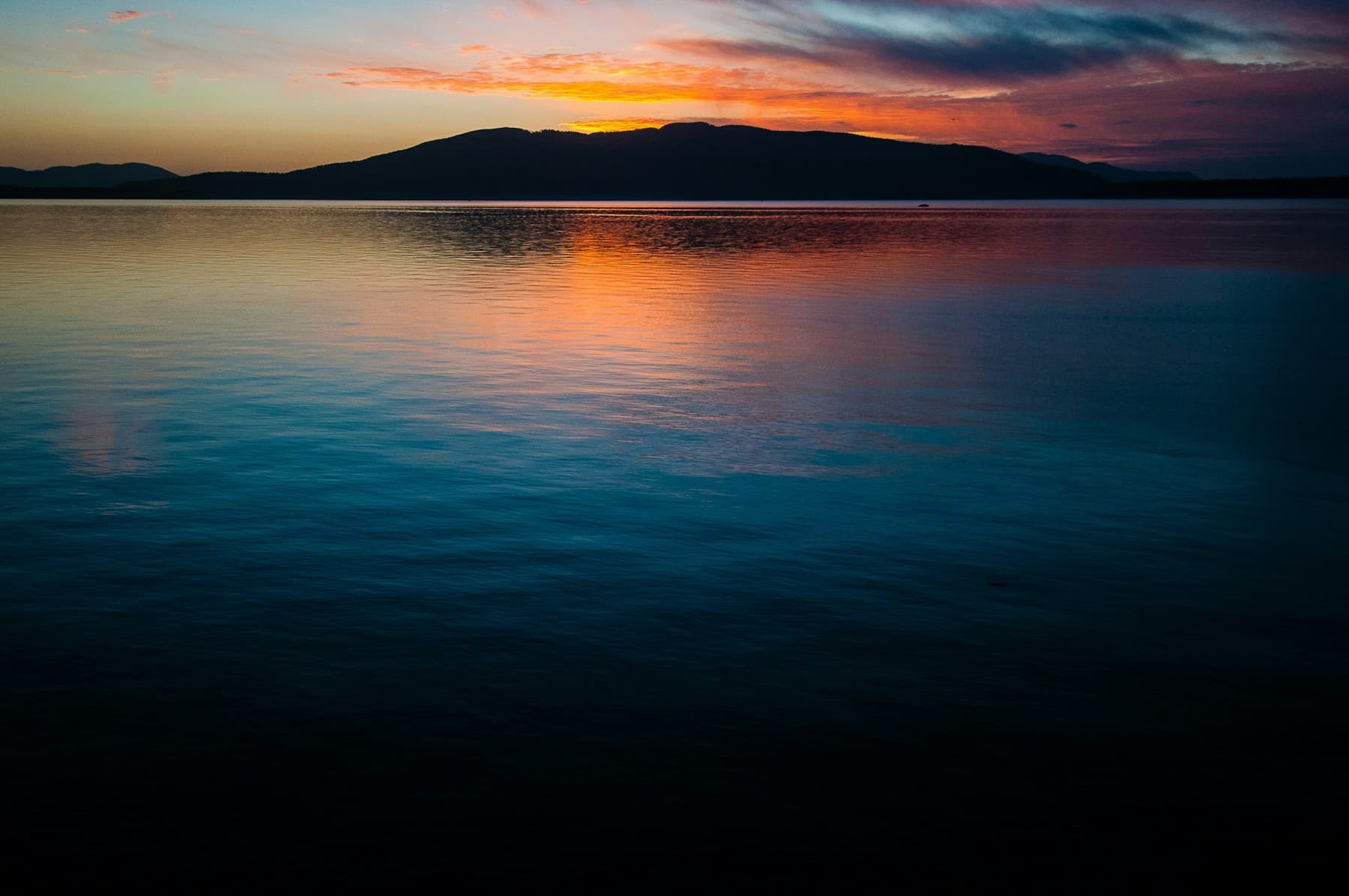 Calm water at dusk with an orange glow on the horizon
