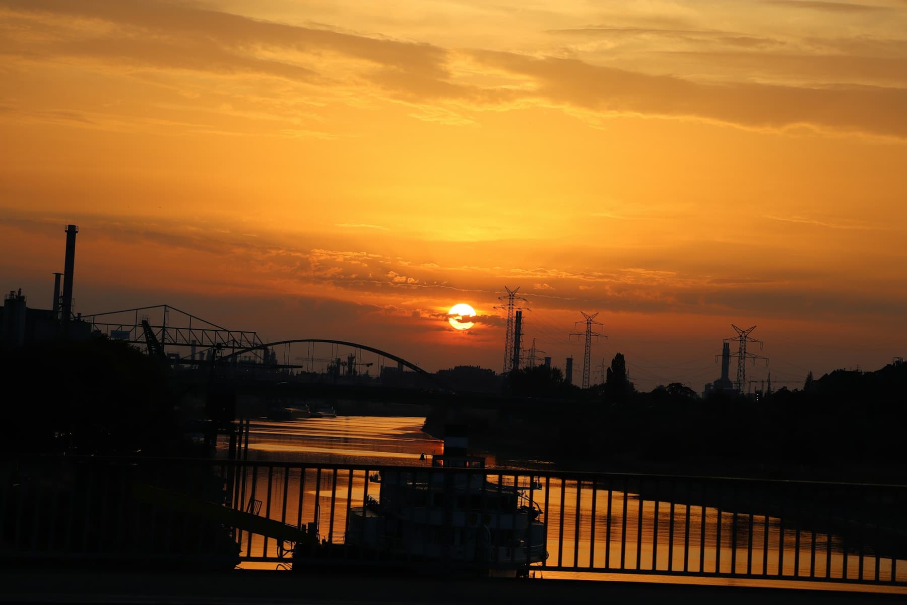 An industrial riverfront in silhouette at sunset