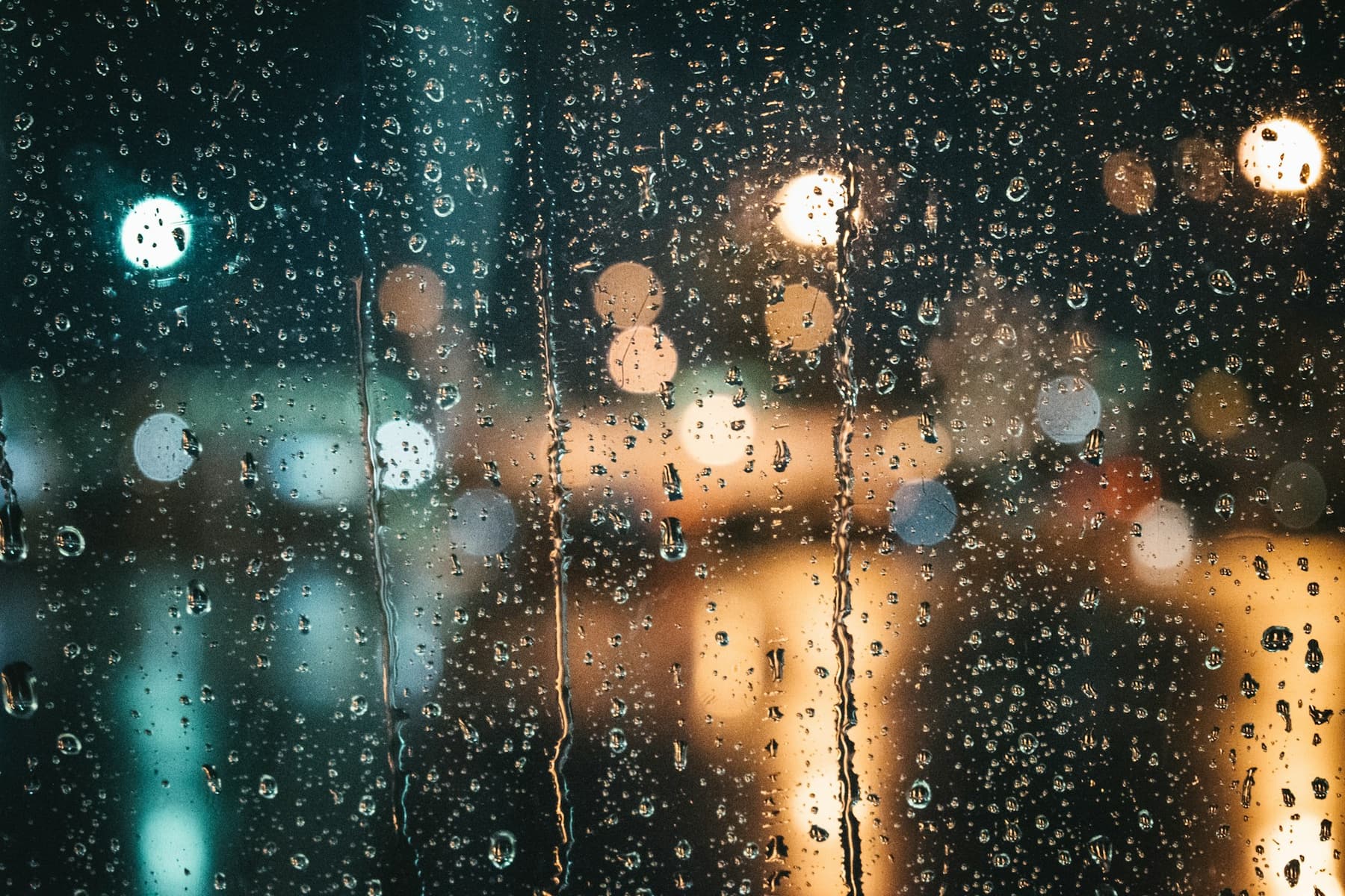 Raindrops on a window at night with blurred lights