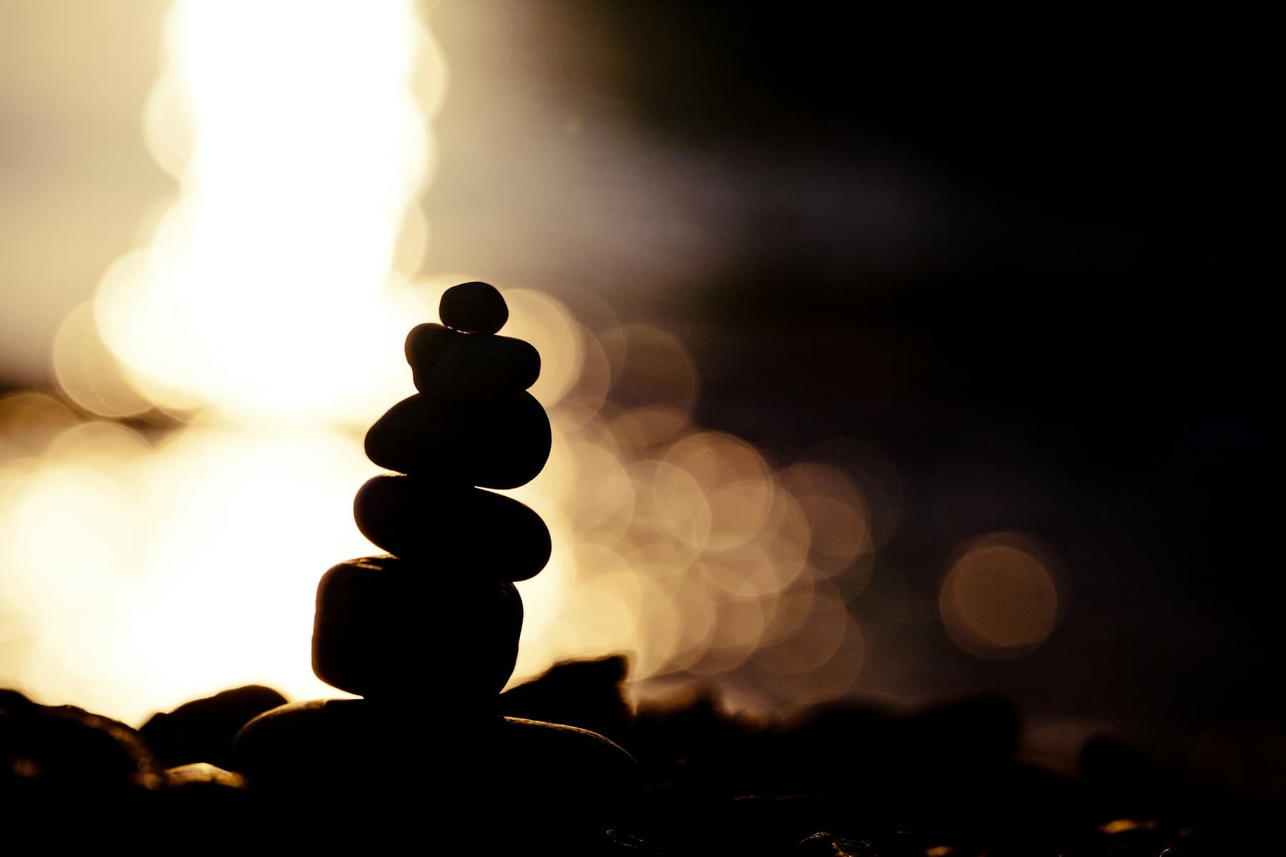 A stack of round stones in silhouette against warm light
